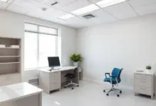 Consultório médico vazio e iluminado por luz natural, com mesa e monitor